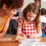 06-elementary-school-teacher-giving-female-pupil-one-XQFZHTV.jpg